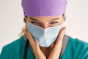 Woman in mask touching face and looking down photo