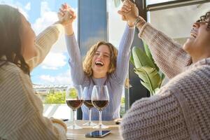 Laughing girlfriends at restaurant with wine photo