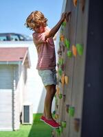 Little boy climbing wall while looking down photo