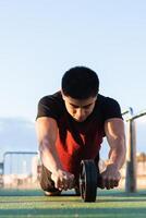 Muscular man doing ab wheel rollout exercise. Young man in action photo
