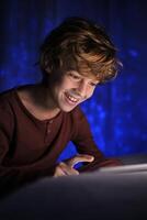 Smiling boy using tablet in dark room photo