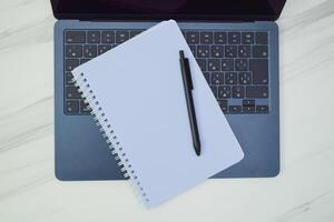 A Notebook and Pen Resting on a Modern Laptop Keyboard photo