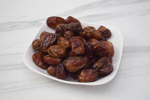 Fresh Dates Are Arranged Nicely In A White Square Dish photo