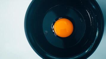 A raw egg yolk rests in a dark bowl with visible shell fragments photo