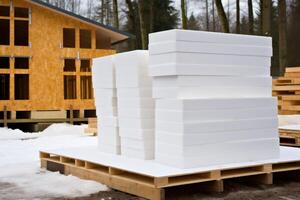 Styrofoam insulation boards stacked on wooden pallet near unfinished house during winter photo