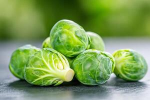Fresh brussels sprouts resting on a dark surface with a green bokeh background photo