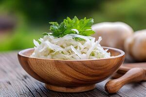Wooden bowl full of sauerkraut with parsley topping on rustic table photo