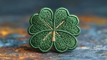 Clover patch on textured bg. This green four-leaf clover patch features detailed embroidery on a textured surface with warm tones. photo