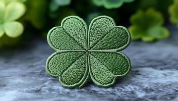 Embroidered green four-leaf clover patch. A green four-leaf clover is on a textured surface, surrounded by blurred foliage, symbolizing good luck. photo