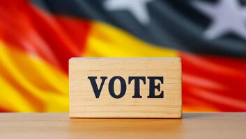 Voting block in front of German flag. A wooden block with VOTE displayed prominently against the backdrop of the German flag, symbolizing civic engagement. photo