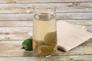 A glass of liquid sitting on a table next to a napkin photo