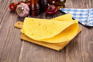 A tortilla on a cutting board with tomatoes and spices photo