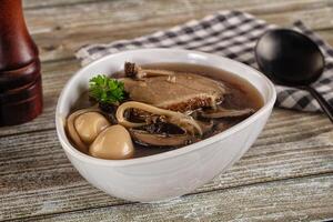 A bowl of soup with meat and mushrooms photo