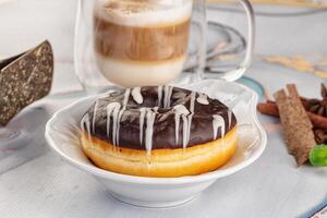 A donut with icing and a cup of coffee photo