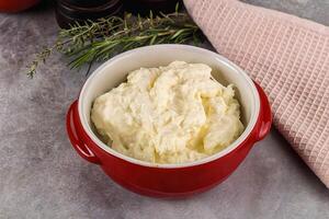A bowl of cream cheese next to a red dish photo