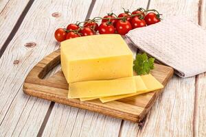 Cheese on a wooden cutting board with tomatoes and herbs photo