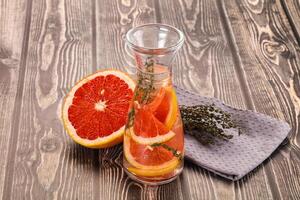 A glass pitcher filled with orange slices and herbs photo