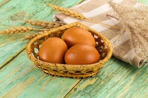 Three eggs in a basket on a wooden table photo