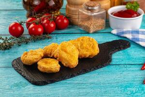 Fried chicken nuggets on a black board with tomatoes and spices photo