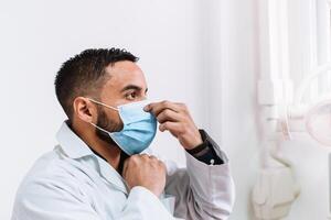 Side View of dentist putting on or taking off a surgical mask. health and hygiene concept. corona virus and pandemic. photo
