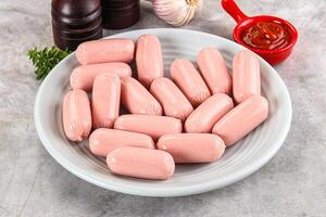 A bowl of sausages on a counter with a bottle of ketchup photo