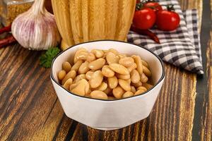 White beans in a white bowl on a wooden table photo