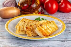 Grilled fish fillet on a plate with tomatoes and garlic photo