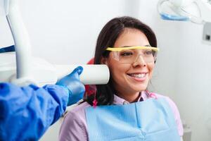 Hispanic woman smiling and happy, while having an oral x-ray. photo