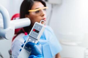 selective focus of a hand with blue latex gloves holding a control to perform an oral x-ray. photo