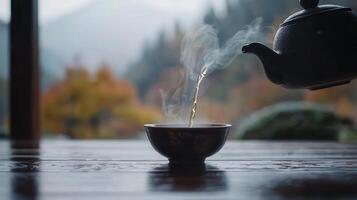 Hot Tea Pouring from Teapot into Bowl on Wooden Table Autumn Background photo