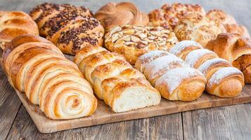 Delicious Assortment of Freshly Baked Breads and Pastries on Wooden Board photo