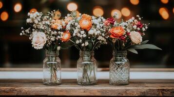 Three rustic mason jars filled with lovely peach and orange flowers perfect for home decor or wedding inspiration photo