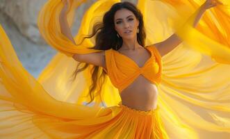 A young Hispanic woman in a flowing yellow dress twirls elegantly, showcasing vibrant fabric and a joyful expression against a bright backdrop. photo