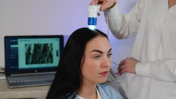 Trichologist performing scalp analysis with digital device video