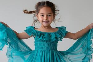 A joyful young girl of Asian descent dances in a flowing teal dress, radiating happiness and playfulness. photo