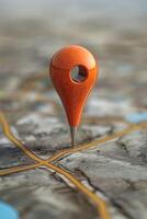 A vibrant orange map pin stands out against a detailed geographical background, symbolizing location and navigation. photo