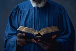 A Black man in a blue robe holds an open book, radiating wisdom and contemplation. photo