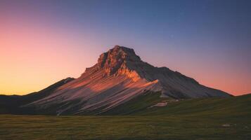 A mountain at sunset with a green field photo