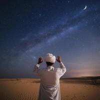 Man praying in the desert at night with the milky and crescent photo