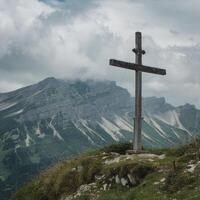 A wooden cross stands on top of a mountain photo