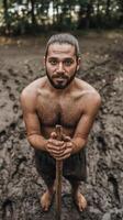 A man with no shirt on standing in the mud photo
