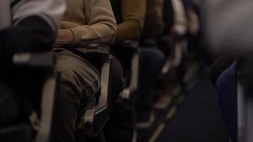 A flight attendant walks from the back along the rows, she distributes food and drinks on board the plane. The passengers are sitting in their seats and watching. video