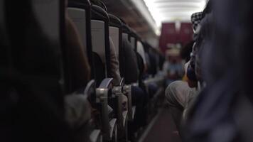 A blurry view of a male steward who distributes food and drinks on board the plane. The passengers are sitting in their seats and watching. View along the row video