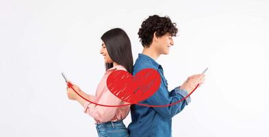 A couple sits back to back, using their smartphones to send affectionate messages to each other. They celebrate love on Valentine's Day, creating a warm connection despite the distance. photo