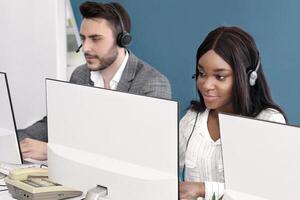 Focused call center operators with headsets working in front of computer monitors at open space office. Team of customer support consultants providing online service to clients photo