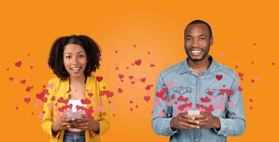 A couple expresses their affection on Valentine's Day by engaging with each other through their smartphones. They smile while reading messages amidst a heart-themed background. photo