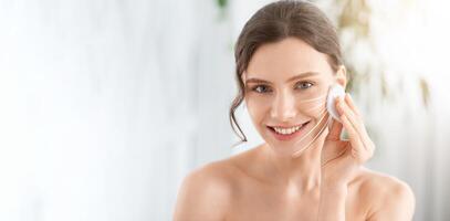 A woman with a serene expression is applying a facial massage technique, enhancing her skin care routine. The setting is bright and calming, perfect for pampering and rejuvenation, copy space photo