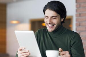 Freelancer having morning coffee at cafe, checking news online on digital tablet, copy space photo