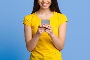 Modern Smartphone In Hands Of Unrecognizable Asian Girl Standing On Purple Background In Studio, Cropped Image With Copy Space photo