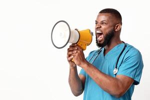 Angry African American man doctor in blue uniform screaming through loudspeaker towards empty space, panorama photo